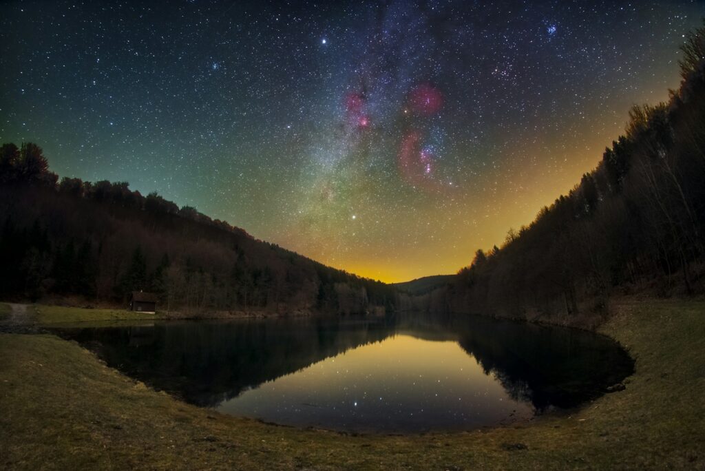 Starry night sky over a calm lake reflecting stars