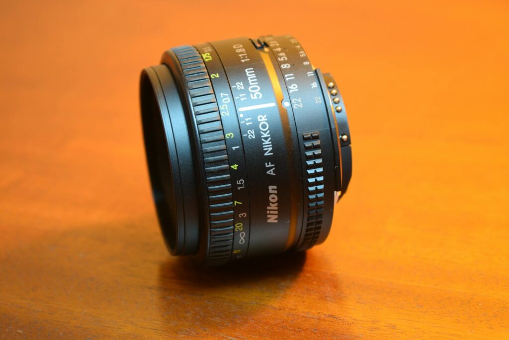 Detailed close-up of a Nikon Nikkor 50mm camera lens on a wooden surface.